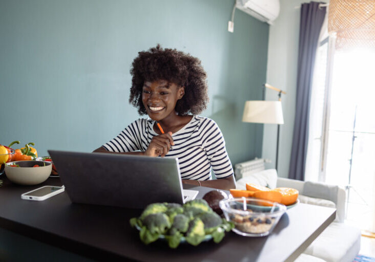 A nutritionist is using a laptop to conduct an online consultation with her patient