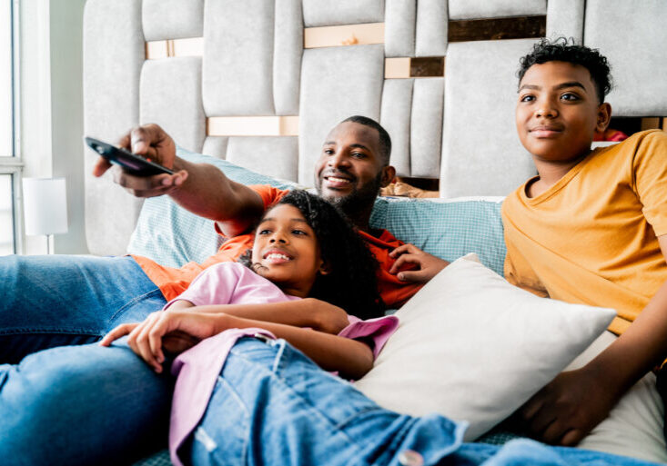 Family watching tv on bedroom at home