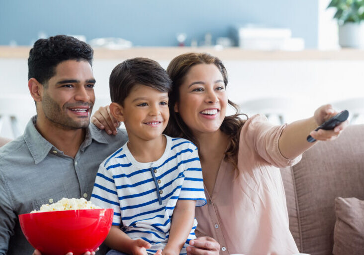 Parents and son watching television in living room at home