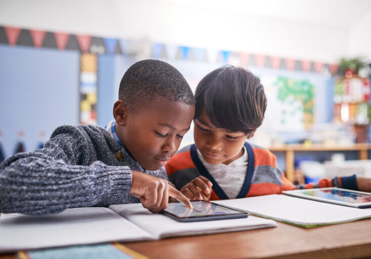 Cropped shot of elementary school children using a tablet in class